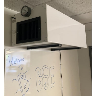 An installed BSE HEPA AIRPRO Commercial 1100 CFM Ambient Air Cleaner hangs from a ceiling in an office environment, above a whiteboard with the welcoming words "Welcome to BSE"