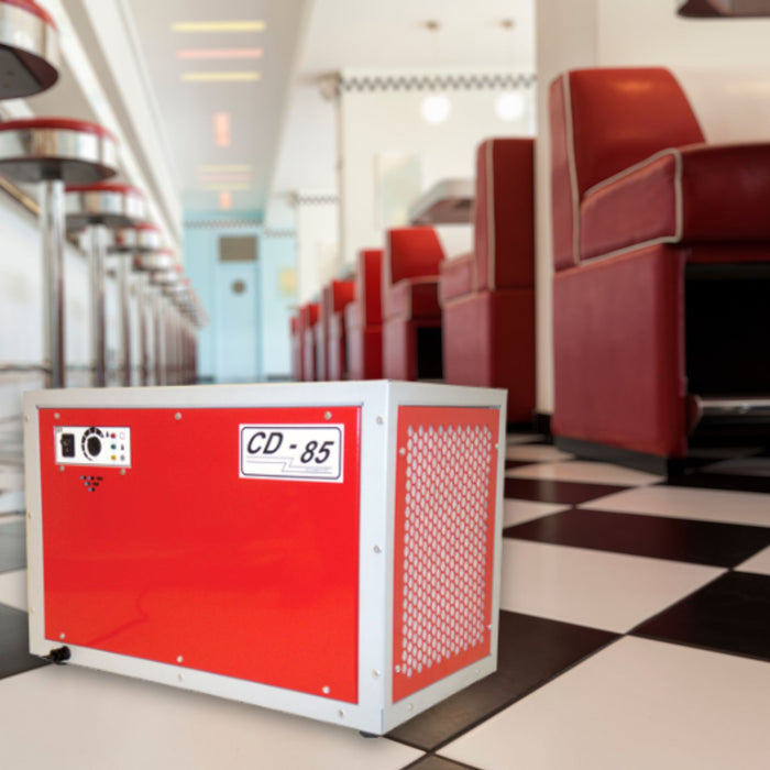 EBac CD85 Commercial Dehumidifier with a capacity of 56 PPD and airflow of 360 CFM, displayed in a diner setting with checkerboard flooring and red diner booths in the background.