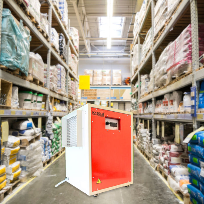 An EBac K100H High-Capacity Dehumidifier with a red front panel and white sides displayed in an industrial warehouse setting.