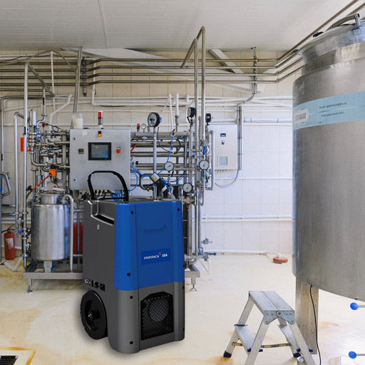 A blue colored TEMP-AIR AD-8000 Airrex industrial dehumidifier on wheels, positioned in a factory setting with pipes and machinery in the background.